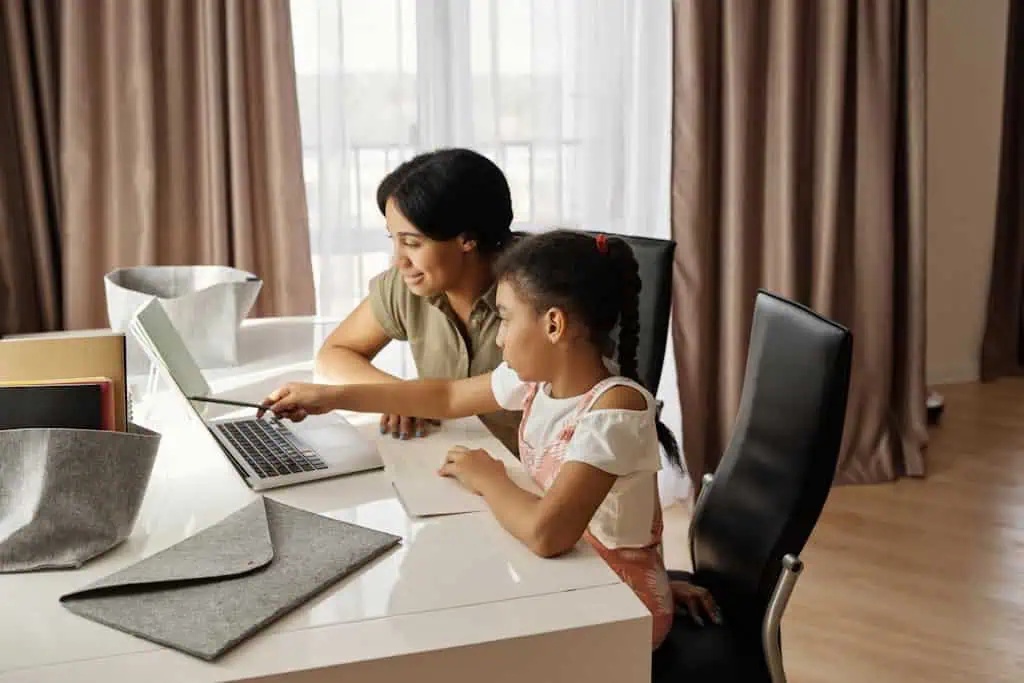 A mother assisting her daughter with online learning on a laptop, promoting education and family bonding.