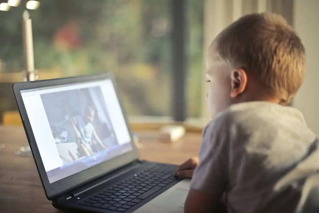 A young boy engrossed in watching content on a laptop in a cozy home setting.